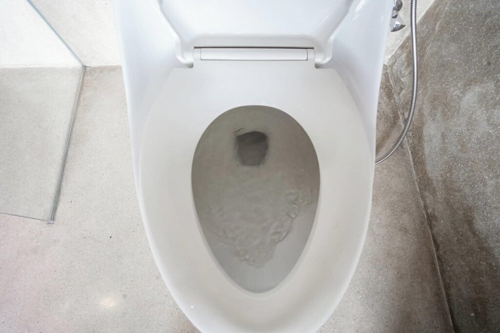 Top view of a white toilet bowl with water flushing inside.